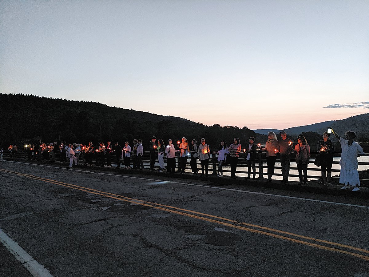 A group gathered on the Callicoon Bridge for a vigil in support of migrants in detention centers at the border.